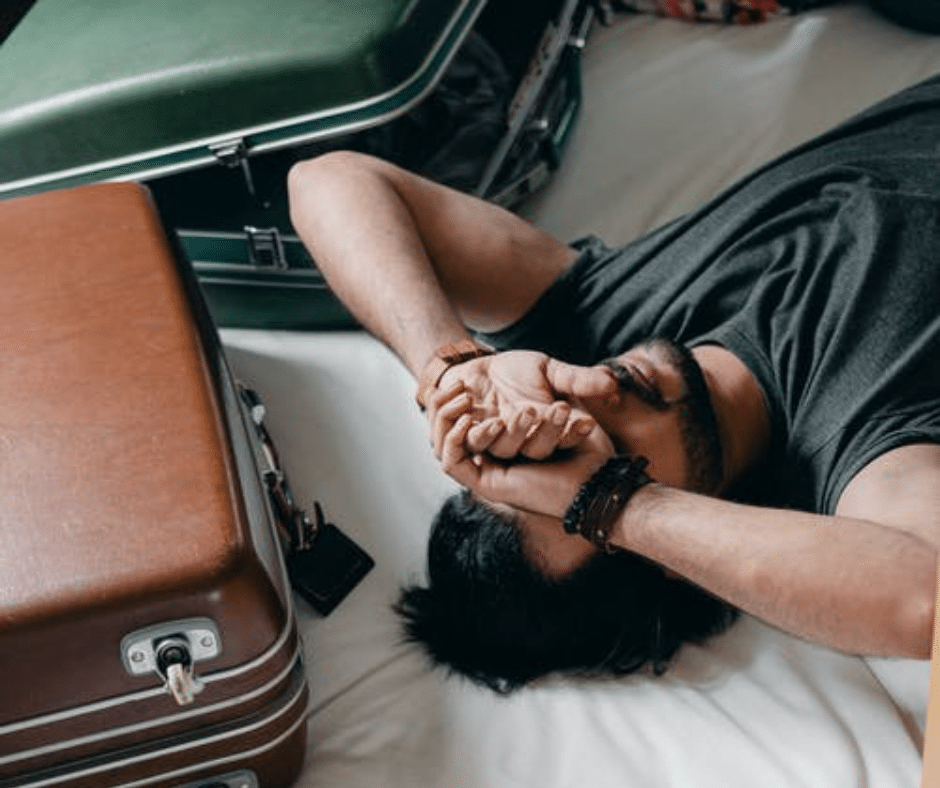Airport chaos leaves man visibly distressed lying on bed with luggage