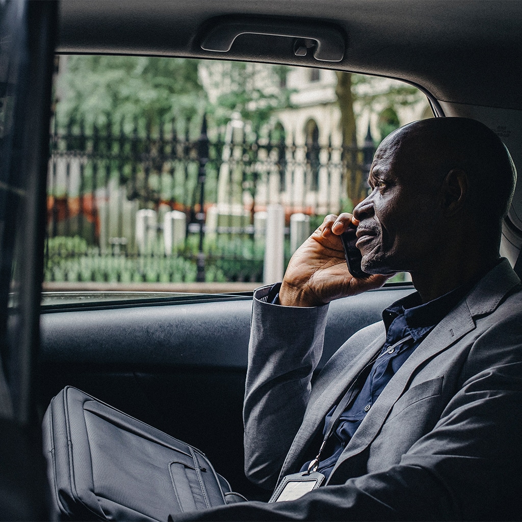 corporate traveller uses phone whilst travelling for work in car