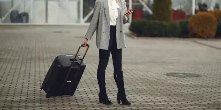 Woman standing in the street with the carry-on luggage