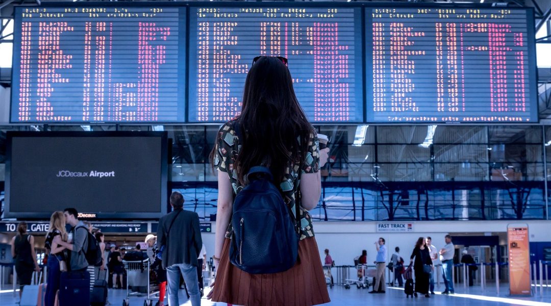 Canadians travelling internationally, pictured looking at flight screens