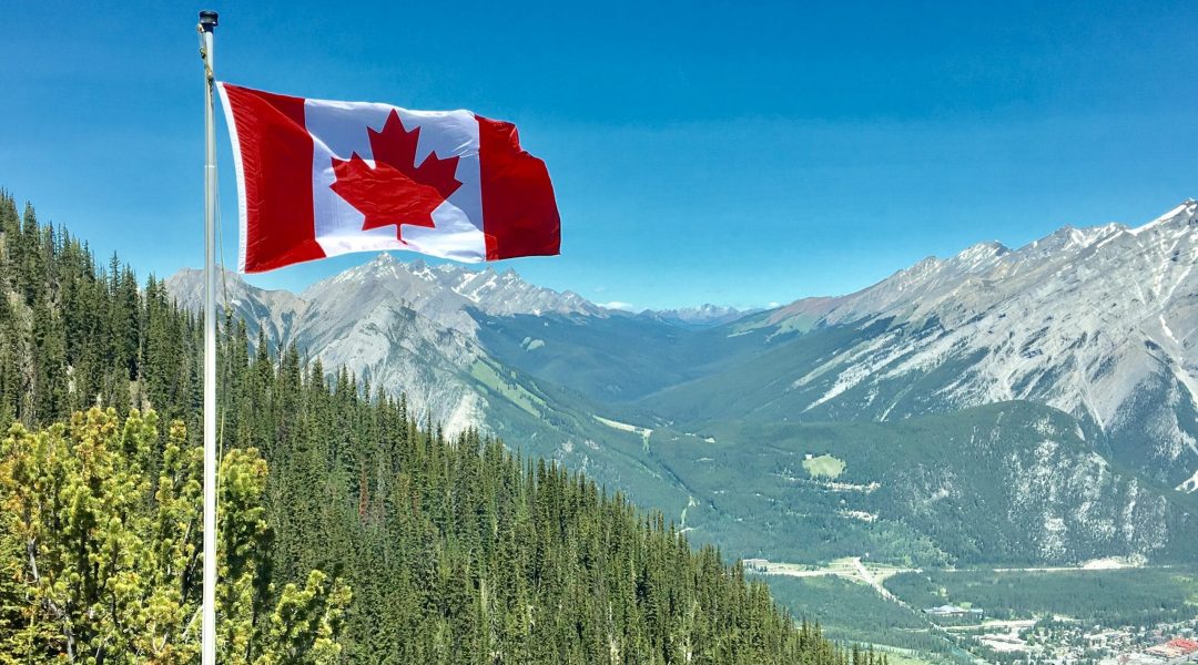 Canadian flag flies over bc mountains as Canada reopens it's borders